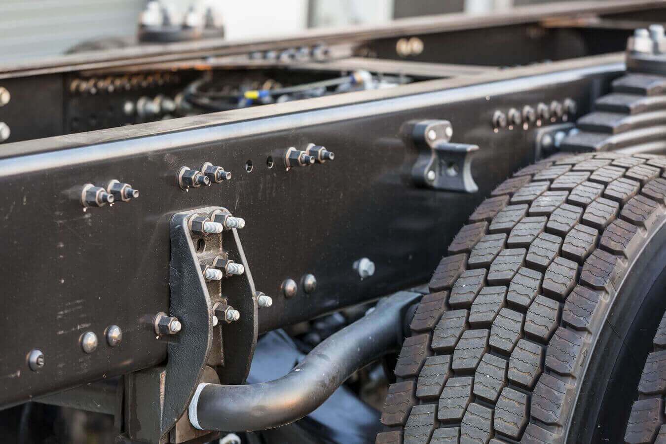 Closeup of a class 8 truck black chassis made from hot rolled steel with silver bolts attached.