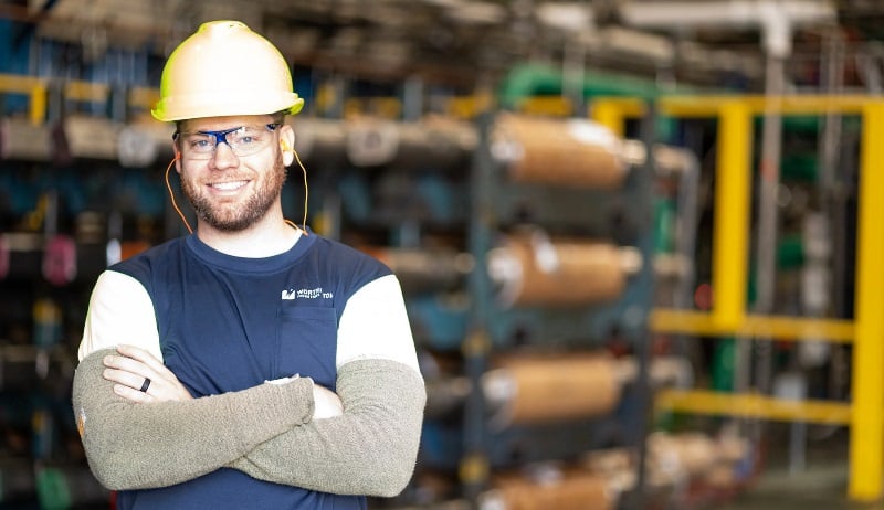 Man in factory with a hard hat and crossed arms
