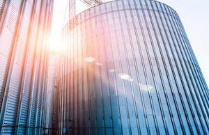 Sunsetting between shiny acrylic coated galvanized steel  grain bins.